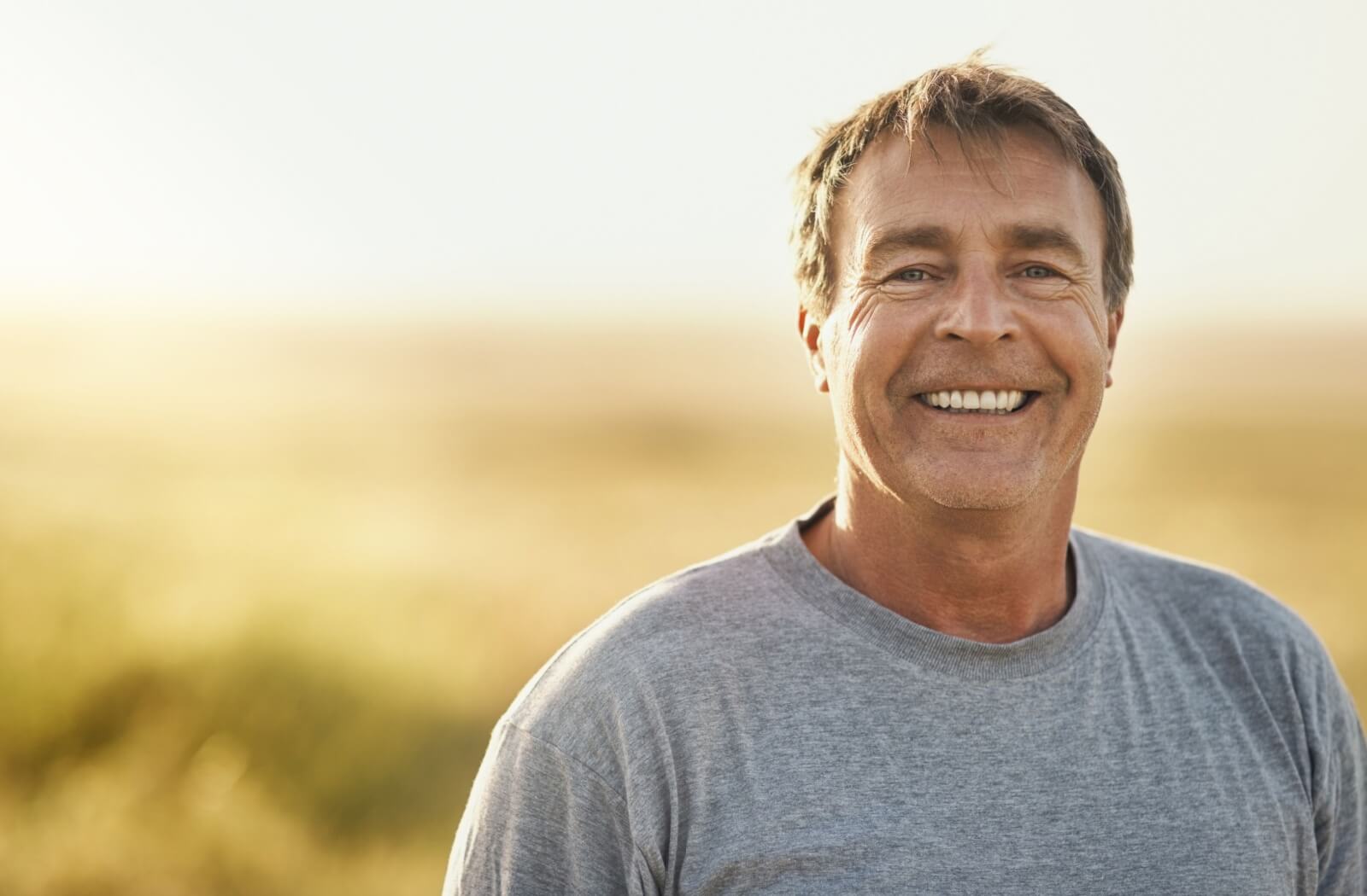 An man smiling with a new set of dental implants that look like natural teeth