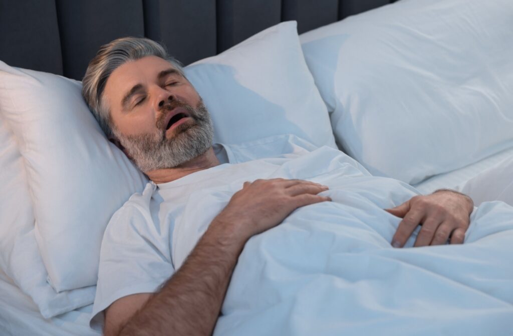 A man snoring while sleeping, mouth open, gasping for air due to sleep apnea.