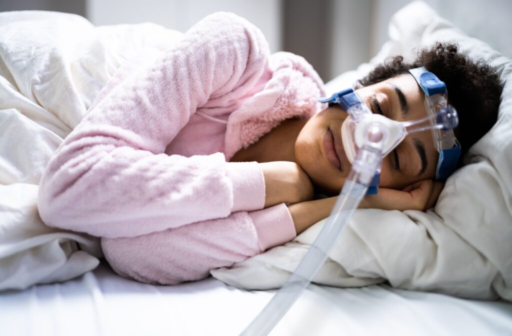 A person in bed sleeping on their side using a CPAP machine.