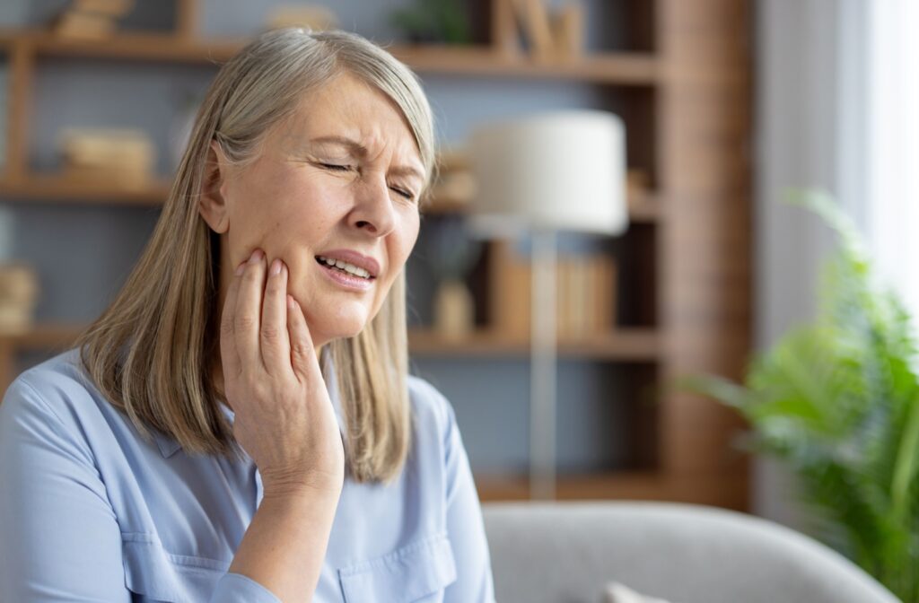 A person holding their jaw and wincing in pain.