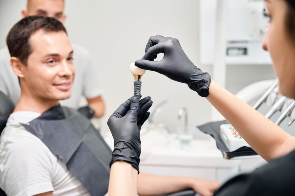 A dentist showing a patient a 3D model of a dental implant.