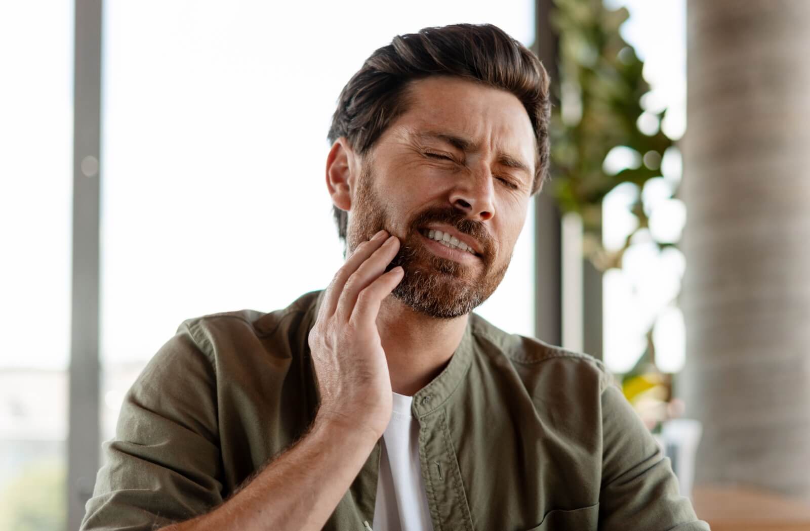 Holding the jaw in pain while sitting indoors.