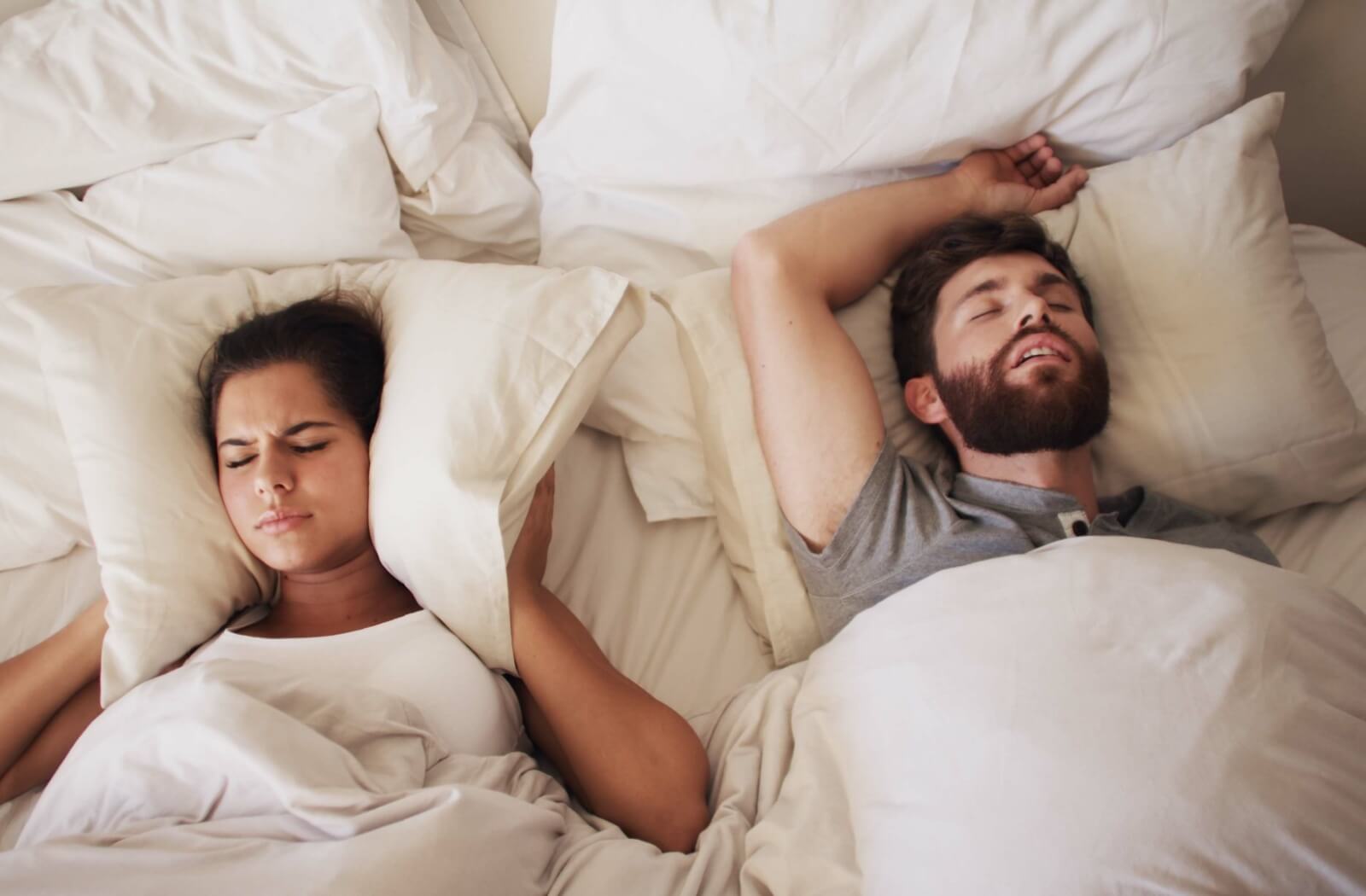 Covering ears with pillows while lying next to a partner who is snoring.